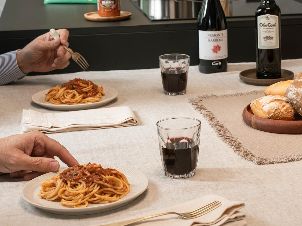 Tisch mit sitzenden Personen, die ein Gericht Spaghetti Bolognese essen