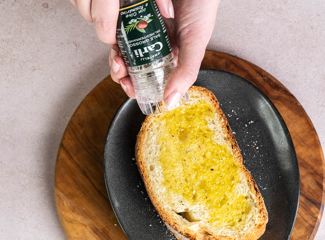 Personne utilisant un moulin à sel sur une tranche de pain avec de l'huile