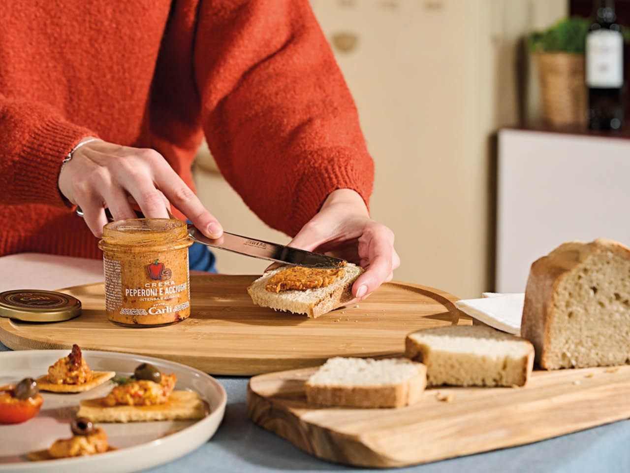 main qui prepare une tartine avec creme poivrons anchois 