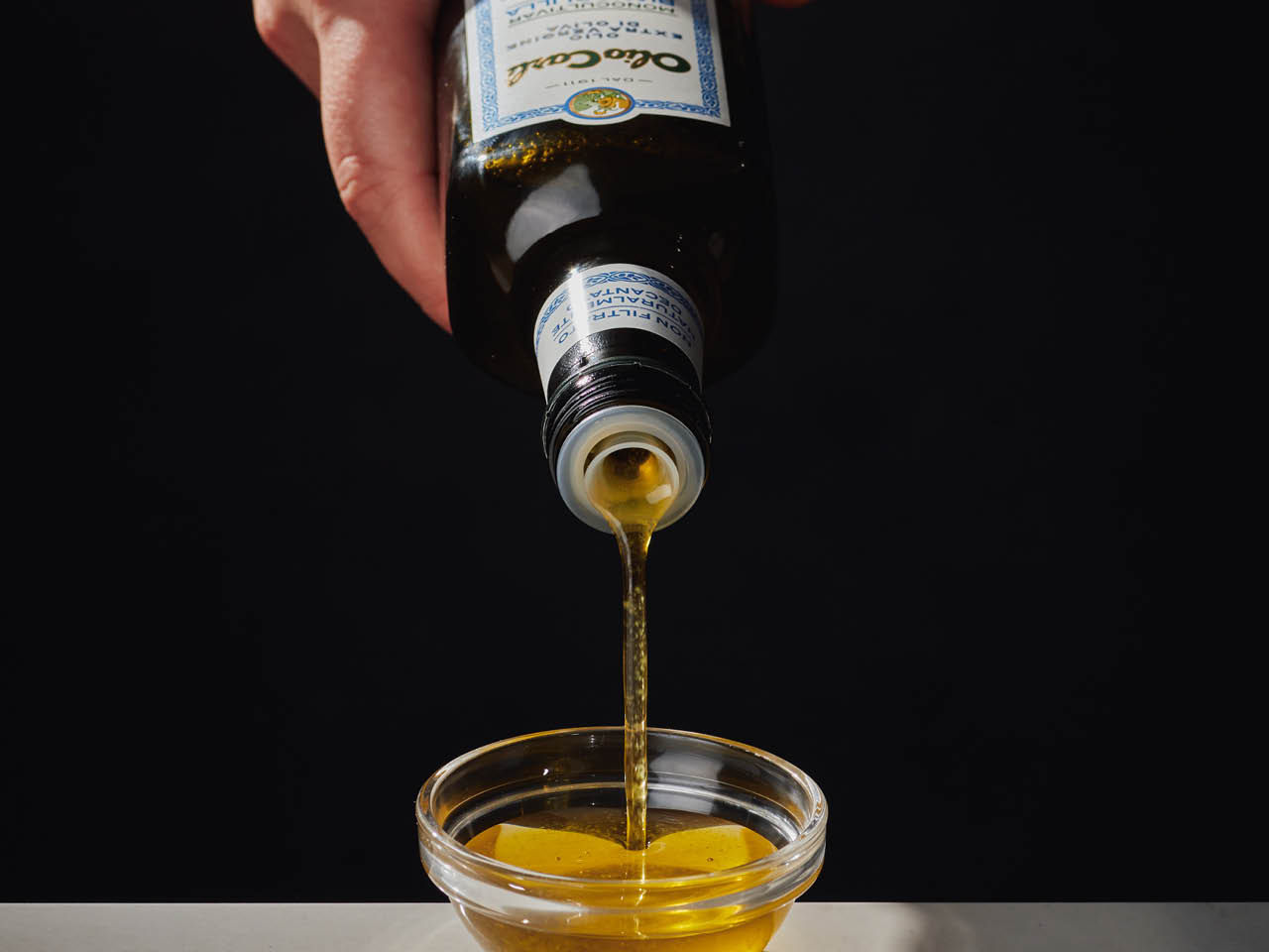 Huile d'olive Biancolilla versée de sa bouteille dans un bol pour la déguster